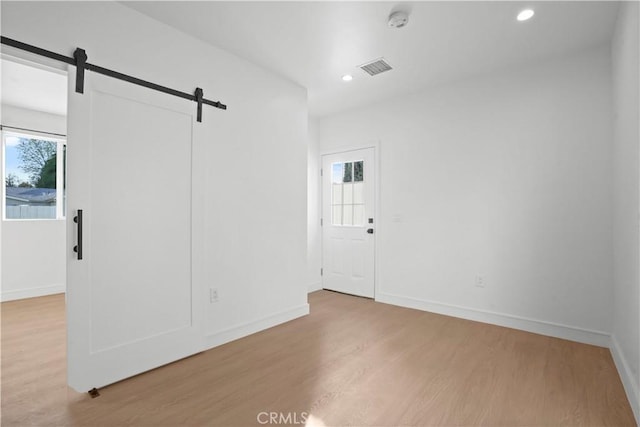 empty room with wood-type flooring and a barn door