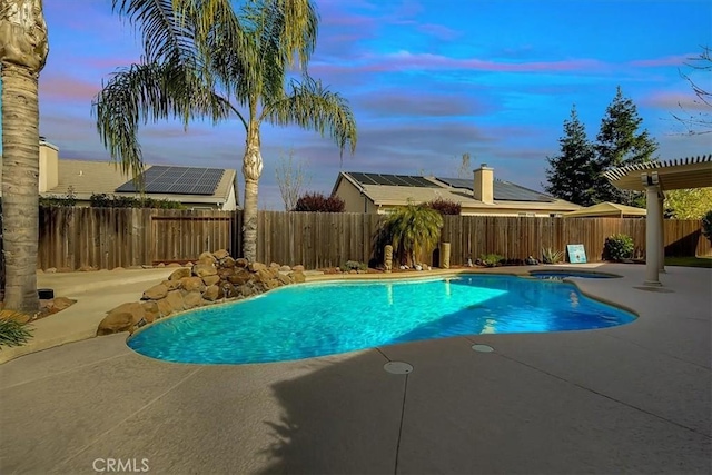 pool at dusk with a patio and an in ground hot tub