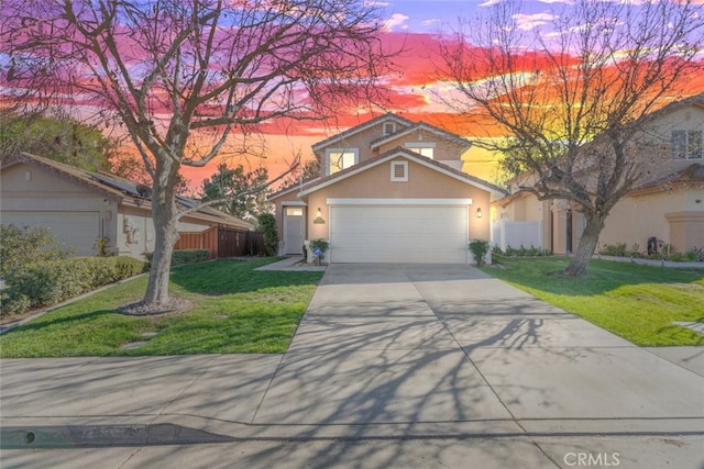 view of front of property with stucco siding, an attached garage, a front yard, fence, and driveway