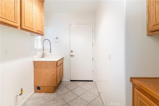 laundry area with cabinets, sink, and light tile patterned floors