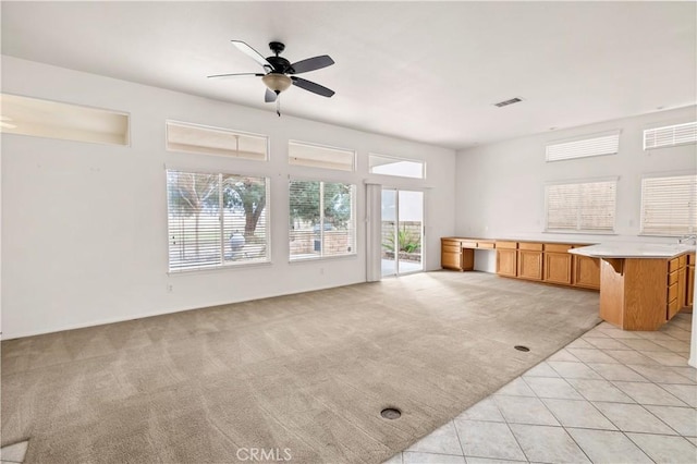 unfurnished living room with light colored carpet and ceiling fan