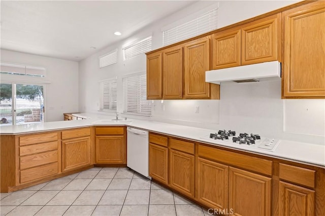 kitchen featuring white appliances, kitchen peninsula, sink, and light tile patterned floors