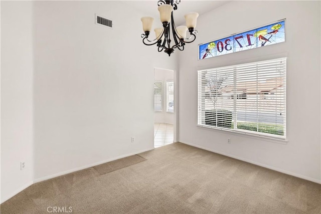 carpeted empty room featuring a chandelier