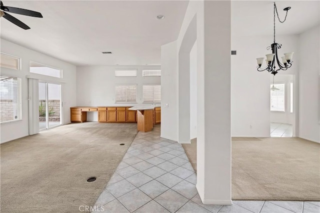 interior space with hanging light fixtures, ceiling fan with notable chandelier, and light colored carpet