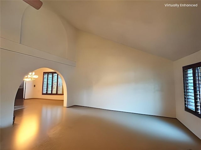 unfurnished room featuring concrete flooring, high vaulted ceiling, and a chandelier