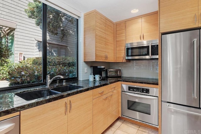 675 S Sierra Ave Unit 15, Solana Beach, CA 92075 - kitchen featuring stainless steel appliances, a sink, light tile patterned floors, decorative backsplash, and dark stone counters