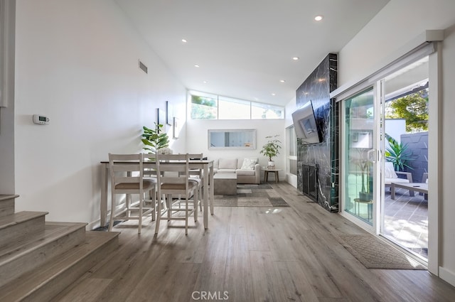 interior space with high vaulted ceiling, hardwood / wood-style floors, and a tile fireplace