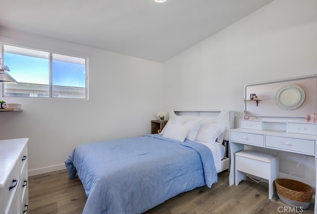 bedroom with vaulted ceiling and light wood-type flooring