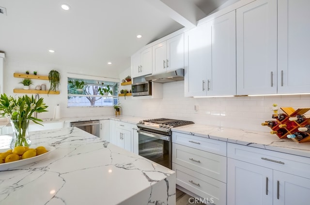 kitchen featuring white cabinetry, stainless steel appliances, light stone countertops, and backsplash