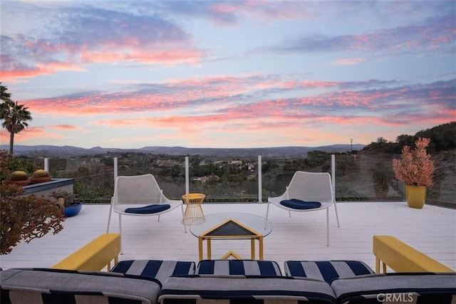 patio terrace at dusk featuring a deck with mountain view