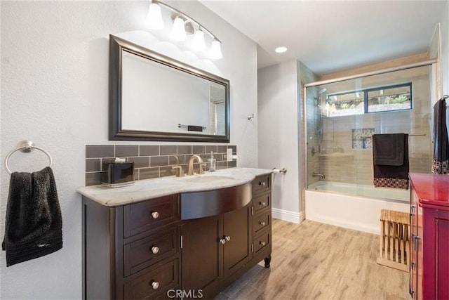 bathroom featuring shower / bath combination with glass door, vanity, wood-type flooring, and decorative backsplash