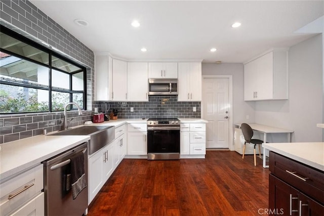 kitchen featuring dark wood-type flooring, stainless steel appliances, white cabinets, decorative backsplash, and sink