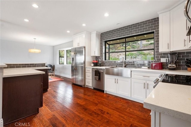 kitchen featuring appliances with stainless steel finishes, white cabinetry, and pendant lighting