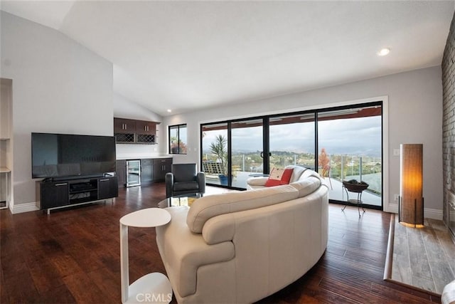 living room featuring bar, vaulted ceiling, and dark wood-type flooring