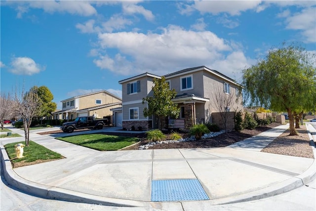 view of front facade featuring a residential view, stone siding, driveway, and stucco siding