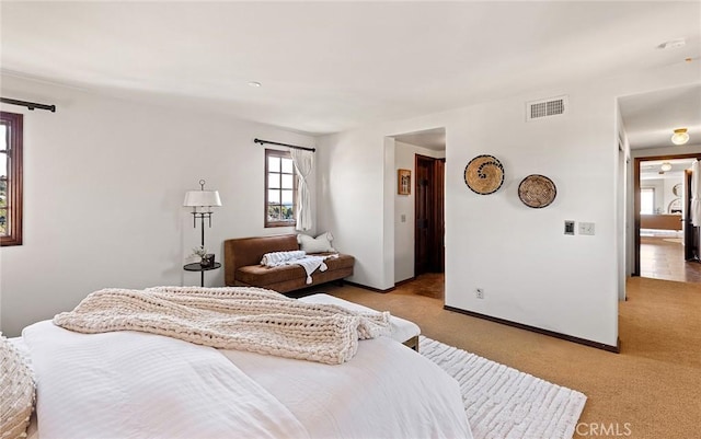 bedroom featuring visible vents, light carpet, and baseboards