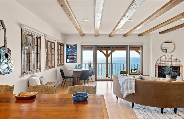 dining area with beam ceiling, a water view, and wood finished floors