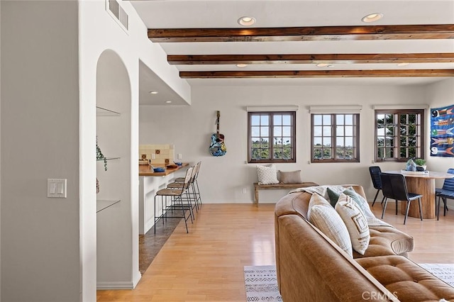 living room with recessed lighting, beam ceiling, visible vents, and light wood finished floors