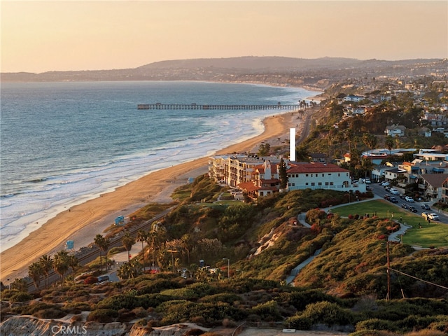 aerial view at dusk with a water view and a beach view