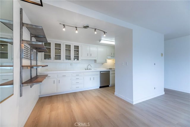 kitchen with sink, white cabinets, stainless steel dishwasher, light hardwood / wood-style floors, and track lighting