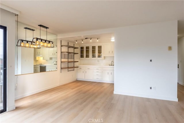 unfurnished living room featuring sink, light hardwood / wood-style floors, and rail lighting