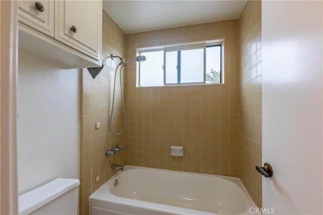 bathroom featuring tiled shower / bath and toilet