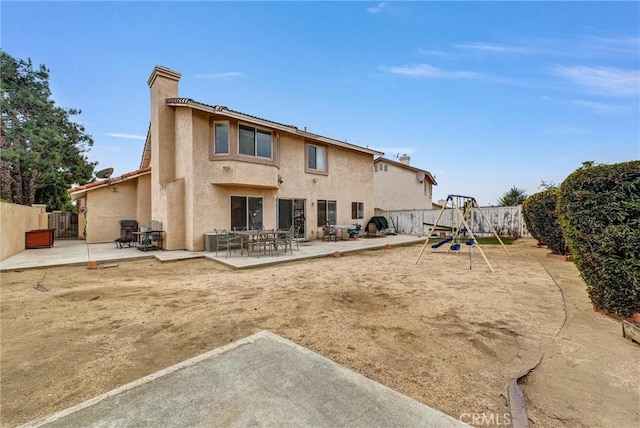 back of property featuring a playground and a patio