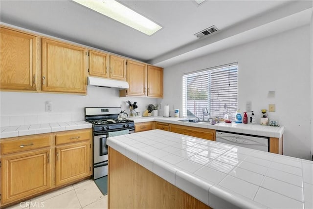 kitchen with sink, white dishwasher, tile countertops, light tile patterned flooring, and stainless steel range with gas cooktop