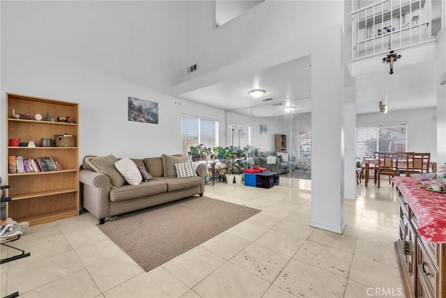 living room with light tile patterned flooring, a towering ceiling, and plenty of natural light