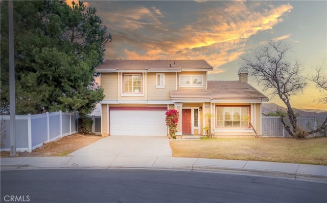 traditional home with concrete driveway, a tile roof, fence, and a front yard