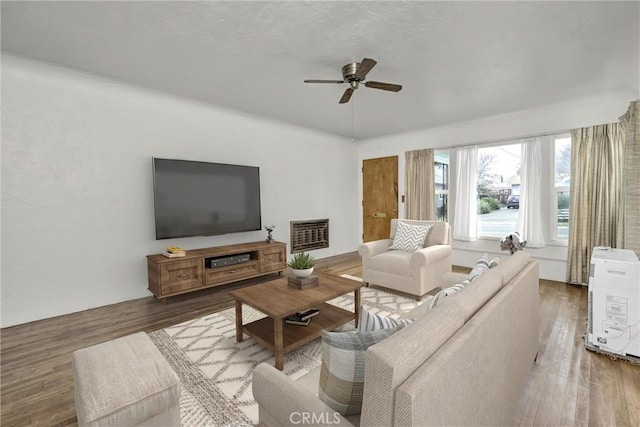 living room with ceiling fan, heating unit, and wood finished floors