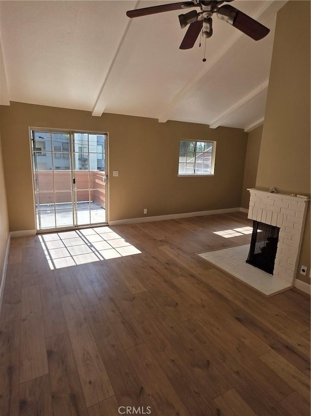 unfurnished living room featuring ceiling fan, a fireplace, lofted ceiling with beams, and hardwood / wood-style floors