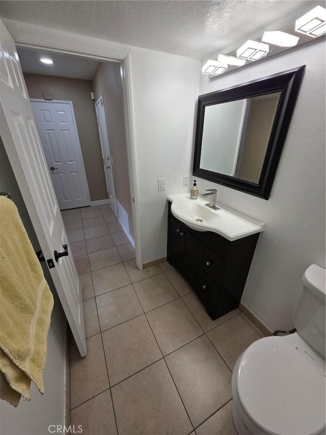 bathroom with tile patterned flooring, vanity, a textured ceiling, and toilet