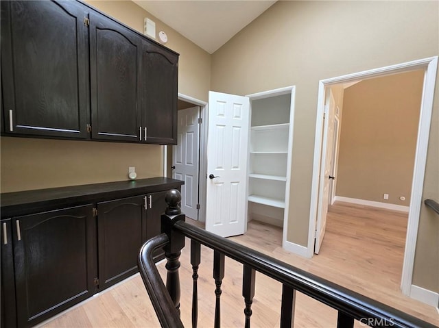 hall with vaulted ceiling and light hardwood / wood-style floors