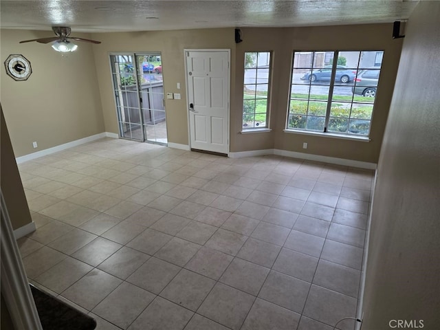 unfurnished room with ceiling fan, light tile patterned flooring, and a textured ceiling