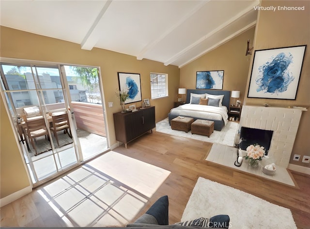 bedroom featuring a brick fireplace, vaulted ceiling with beams, access to outside, and light hardwood / wood-style flooring