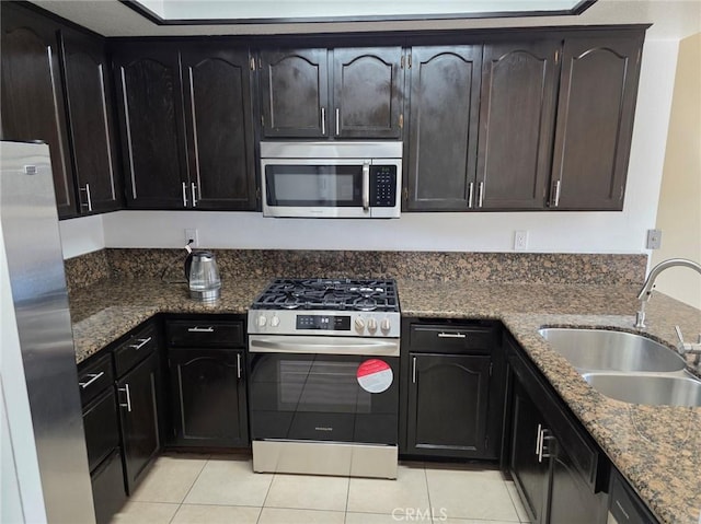 kitchen with light tile patterned flooring, appliances with stainless steel finishes, sink, and dark stone counters