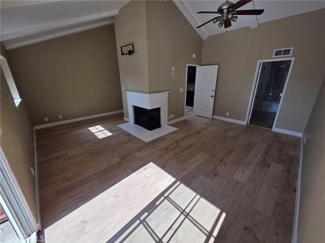 unfurnished living room featuring a multi sided fireplace, wood-type flooring, ceiling fan, and high vaulted ceiling