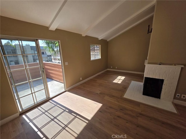 unfurnished living room featuring lofted ceiling with beams, wood-type flooring, and a brick fireplace