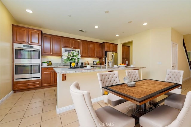 kitchen featuring appliances with stainless steel finishes, sink, a center island with sink, and light tile patterned floors