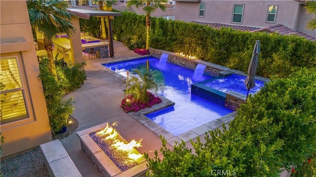 view of swimming pool featuring a hot tub, a fire pit, a fenced in pool, and a patio