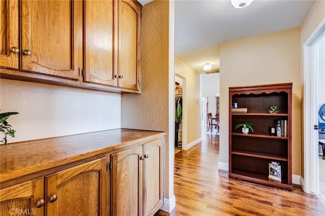 corridor with baseboards and light wood finished floors