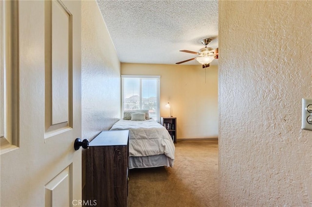 bedroom featuring a textured ceiling, a textured wall, ceiling fan, and carpet