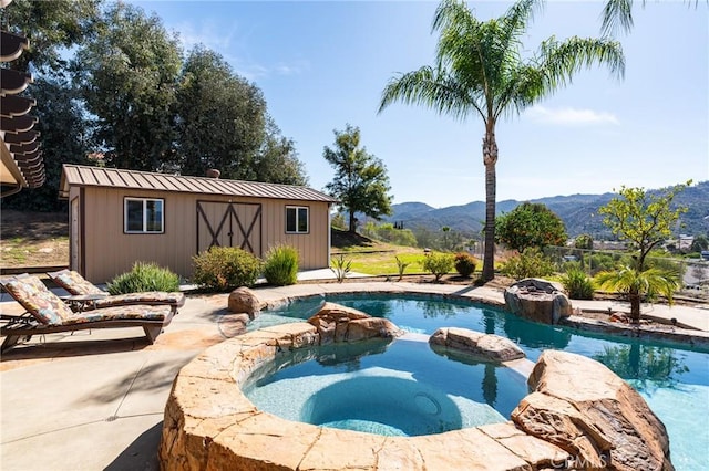 view of pool featuring an outbuilding, a pool with connected hot tub, and a mountain view