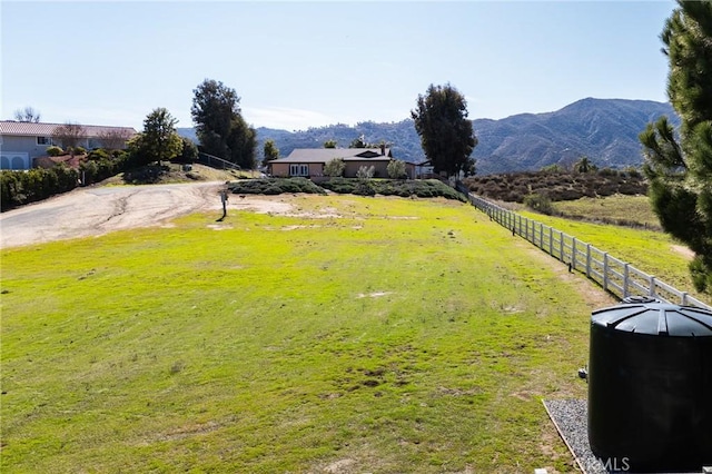 view of yard with a rural view, fence, and a mountain view