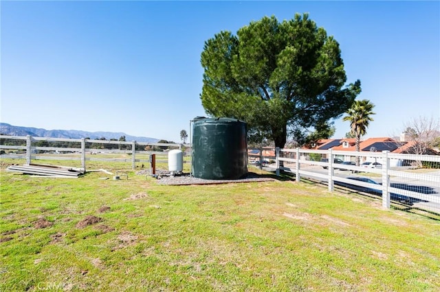 view of yard featuring a rural view, fence, and a mountain view