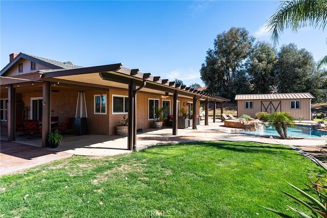 back of house with stucco siding, a lawn, a patio area, an outdoor pool, and an outdoor structure