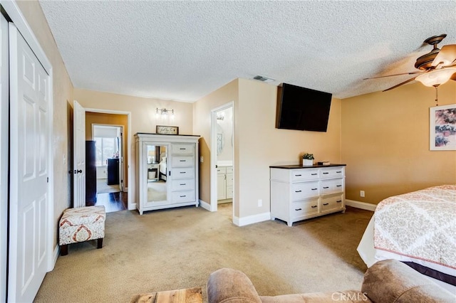 carpeted bedroom featuring a textured ceiling, connected bathroom, visible vents, a ceiling fan, and baseboards