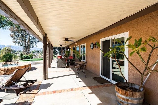 view of patio with ceiling fan and a mountain view