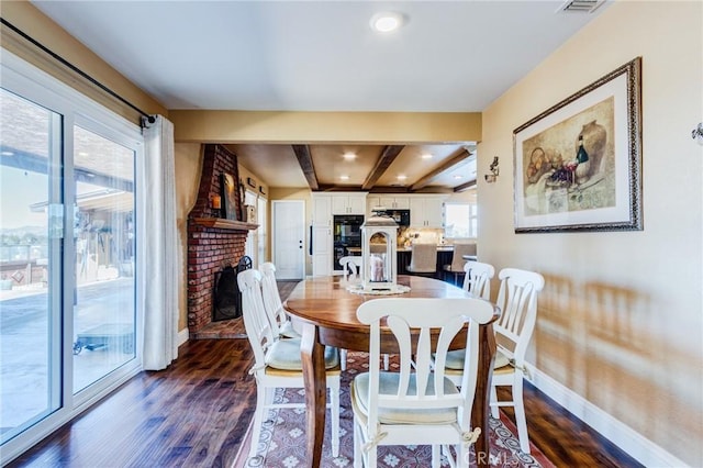 dining area with dark wood-type flooring, beamed ceiling, a fireplace, and baseboards